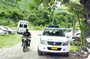 Police vehicles parked in August Town yesterday near where Constable James Grant was shot dead on Monday. (Photo: Michael Gordon/Jamaica Observer)