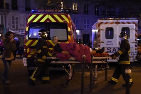 Rescuers workers evacuate a man on a stretcher near the Bataclan concert hall in central Paris, on November 13, 2015. A number of people were killed and others injured in a series of gun attacks across Paris, as well as explosions outside the national stadium where France was hosting Germany. AFP PHOTO / DOMINIQUE FAGET