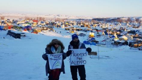 A couple of the remaining activists, hold up signs as they grapple with plunging temperatures that make conditions more difficult at the protest camp in Cannon Ball, North Dakota, December 14, 2016. Picture taken December 14, 2016. REUTERS/Valerie Volcovici